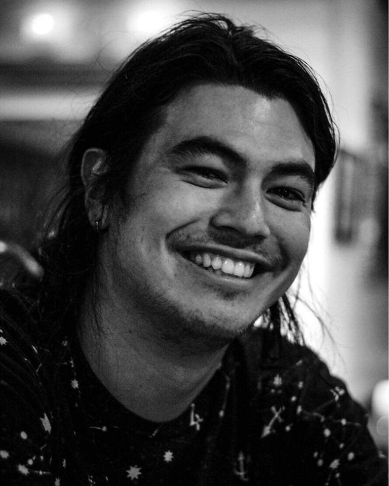 Une photo en noir et blanc de Jason Lentz, un homme aux cheveux longs, souriant à la caméra.