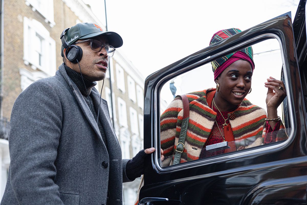 Reinaldo Marcus Green et Lashana Lynch dans le rôle de Rita Marley debout près d'une voiture noire à l'ancienne sur le tournage de One Love