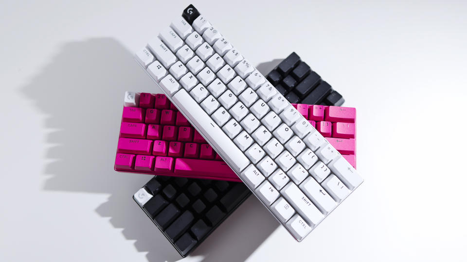 Trois claviers Logitech G Pro X 60 – un blanc, un rose et un noir – sont empilés les uns sur les autres sur un fond blanc.