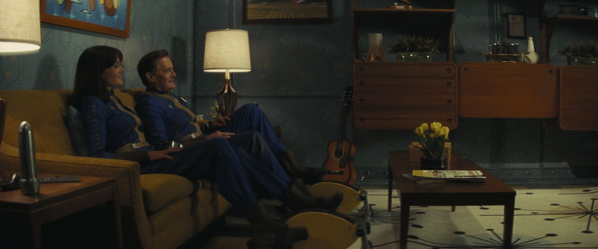 Lucy (Ella Purnell) et son père Hank (Kyle MacLachlan) assis sur un canapé souriant dans un salon Vault