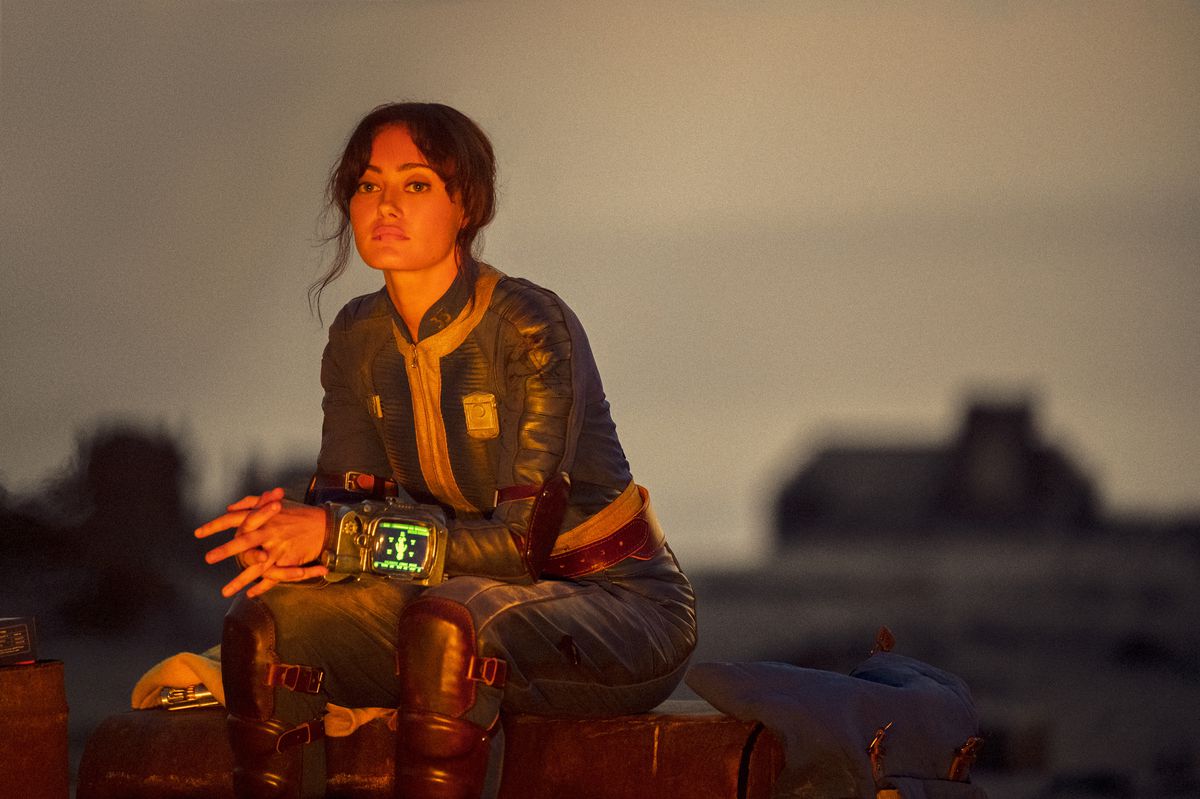 Lucy (Ella Purnell) assise près d'un feu, l'air solennelle dans une photo de Fallout