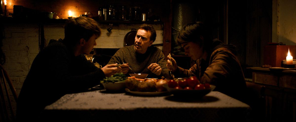 Paul (Nicolas Cage) et les jumeaux de 15 ans Thomas (Maxwell Jenkins) et Joseph (Jaeden Martell) sont assis à table dans une pièce sombre et sombre dans Arcadian.