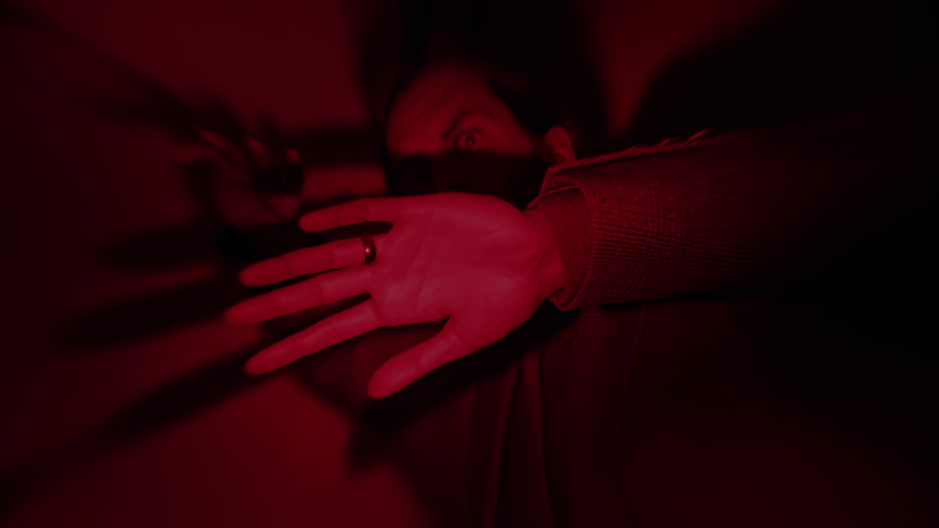 Capture d'écran d'Alan Wake 2 montrant Alan piégé dans un endroit sombre sous une lumière rouge