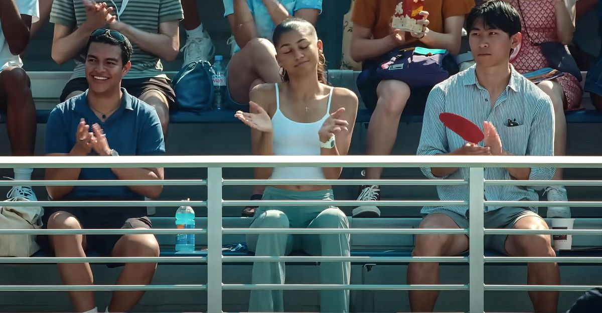 Le joueur de tennis Tashi (Zendaya) est assis dans les tribunes lors d'un match des Challengers de Luca Guadagnino.  Les fans autour d'elle applaudissent ce qui se passe sur le terrain, mais elle sourit et hausse les épaules, les yeux fermés.