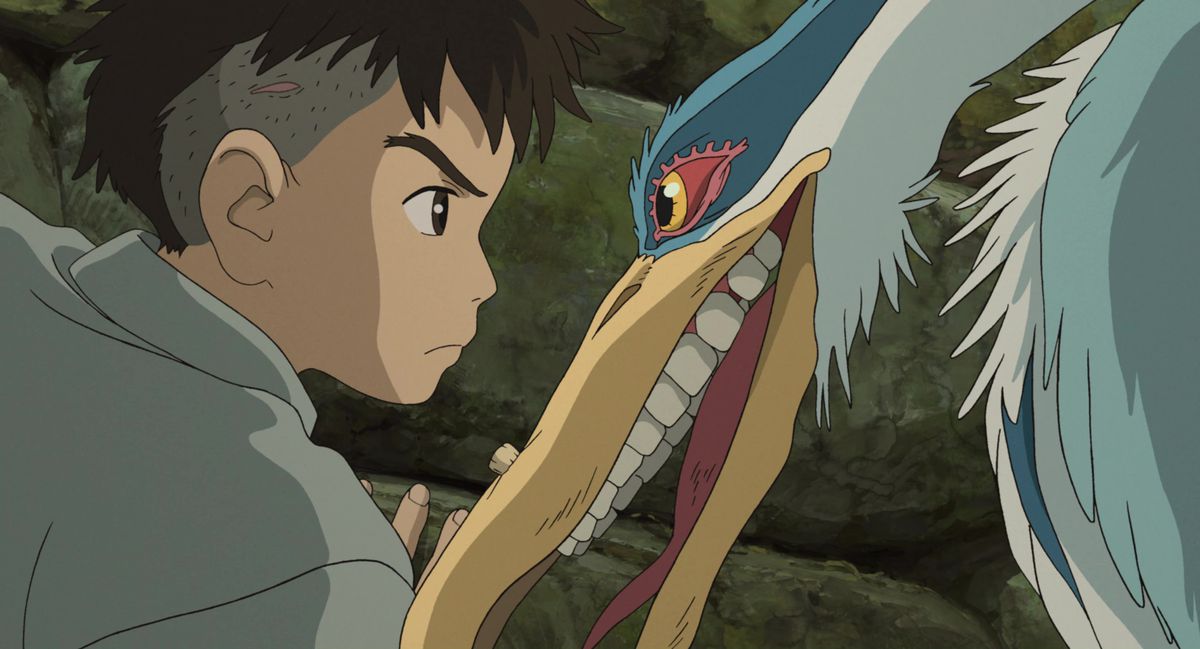 Mahito et un héron cendré aux dents humaines inquiétantes se regardent face à face dans le film d'animation de Hayao Miyazaki Le Garçon et le Héron
