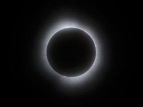 Des éruptions solaires bordent la lune alors qu'elle passe devant le soleil pendant la phase de totalité d'une éclipse solaire totale, à Kingston, en Ontario, le lundi 8 avril 2024.