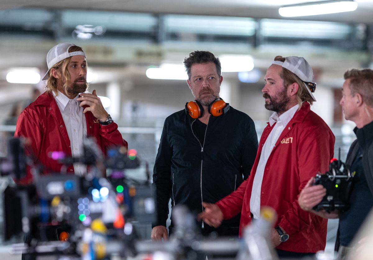 Ryan Gosling et le cascadeur Logan Holladay, tous deux vêtus de valets de chambre rouges, discutent avec David Leitch sur le tournage de The Fall Guy