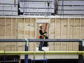Un employé travaille sur un élément de maison modulaire à Calgary.  Le gouvernement canadien autorisera des périodes d’amortissement de 30 ans sur les prêts hypothécaires assurés pour les premiers acheteurs de maisons nouvellement construites.