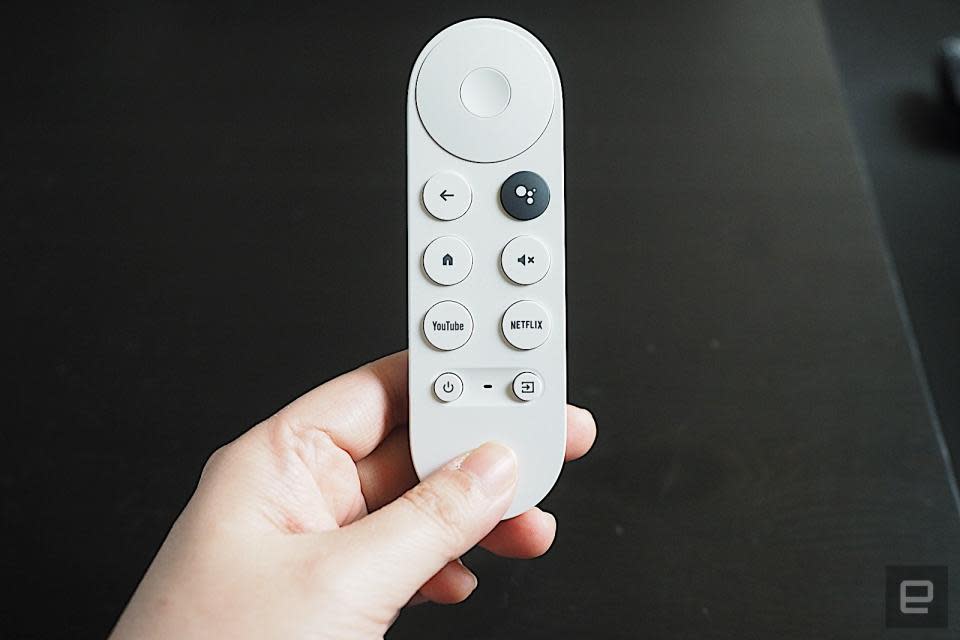 Télécommande vocale pour Chromecast avec télécommande Google TV (HD).  La main d'une personne tient la télécommande blanche sur un fond sombre.