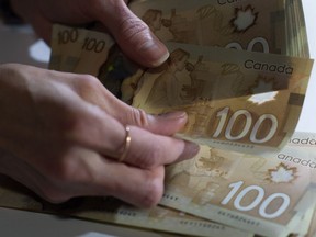 Tous les ménages canadiens, quel que soit leur spectre économique, ont connu une augmentation de leurs revenus et de leur richesse depuis la période pré-pandémique, mais un rapport suggère que l'écart entre les plus hauts revenus et les groupes à faible revenu s'est creusé à un niveau jamais vu depuis 2015. Les billets de 100 $ canadiens sont dénombré à Toronto, le 2 février 2016.