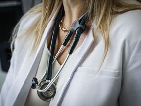 Un médecin porte une blouse de laboratoire et un stéthoscope dans une salle d'examen d'une clinique de santé de Calgary, en Alberta, le vendredi 14 juillet 2023.