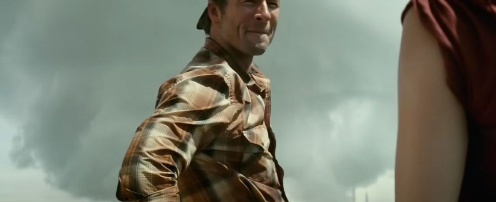 Glen Powell in the trailer for Twisters with a tornado behind him.