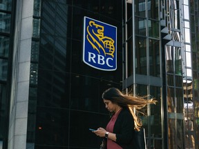 Une femme passe devant une pancarte de la Banque Royale du Canada dans le quartier financier de Toronto.