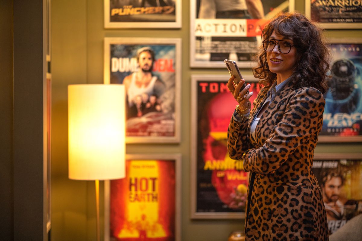 Dans une scène de The Fall Guy, la productrice Gail Meyer (Hannah Waddingham, dans une robe portefeuille à imprimé léopard) se tient dans une pièce bordée d'affiches de films, tenant son téléphone
