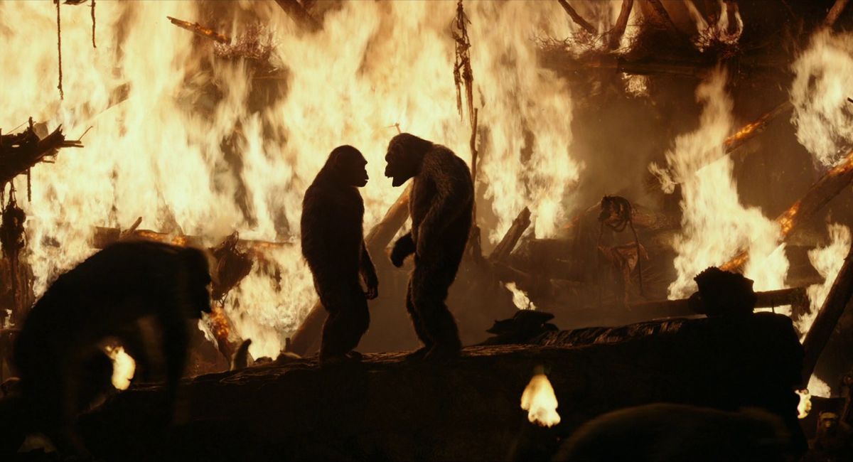 Deux singes se faisant face au sommet d'une plate-forme entourés de singes fuyant une structure en feu.