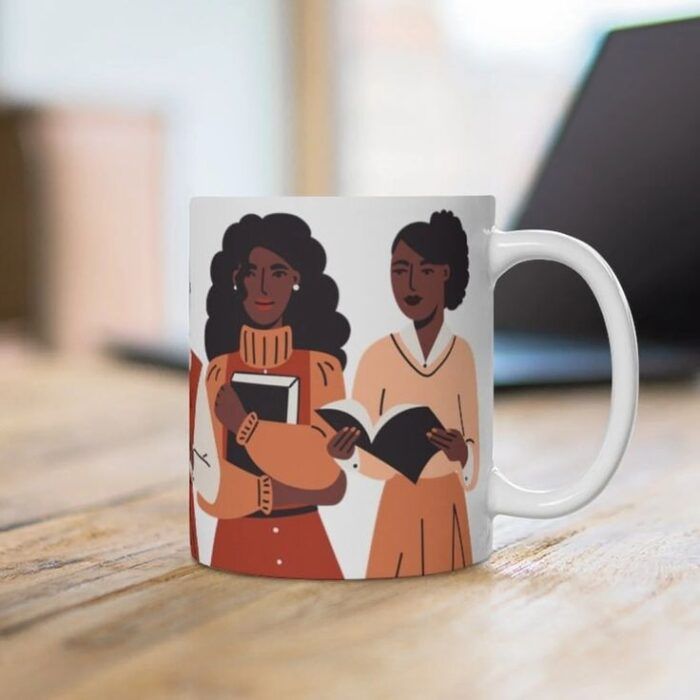 une tasse blanche avec des illustrations de femmes noires vêtues de couleurs chaudes tenant des livres 