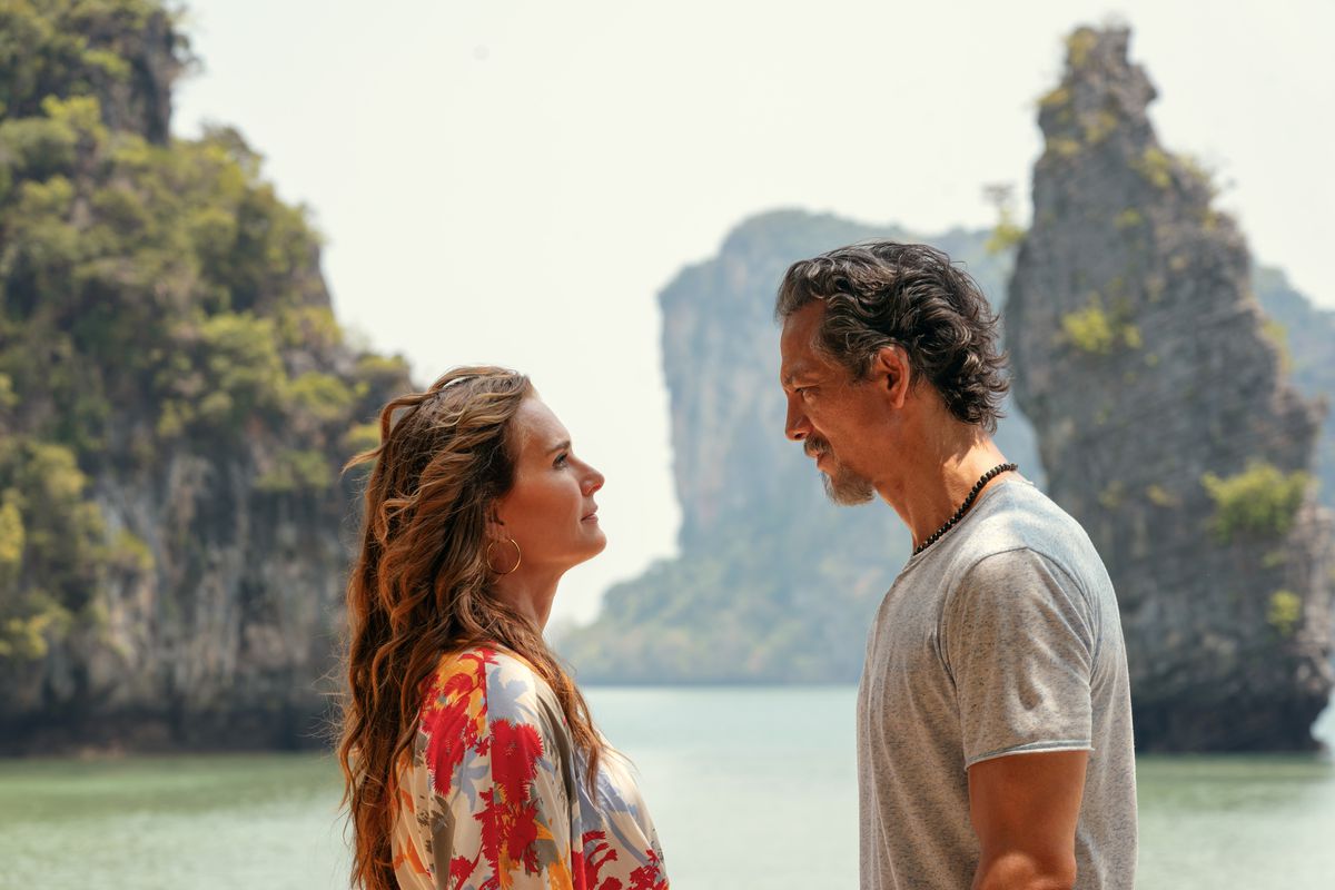 Une jeune femme regardant un homme devant une vue pittoresque d’un paysage tropical dans Mother of the Bride.
