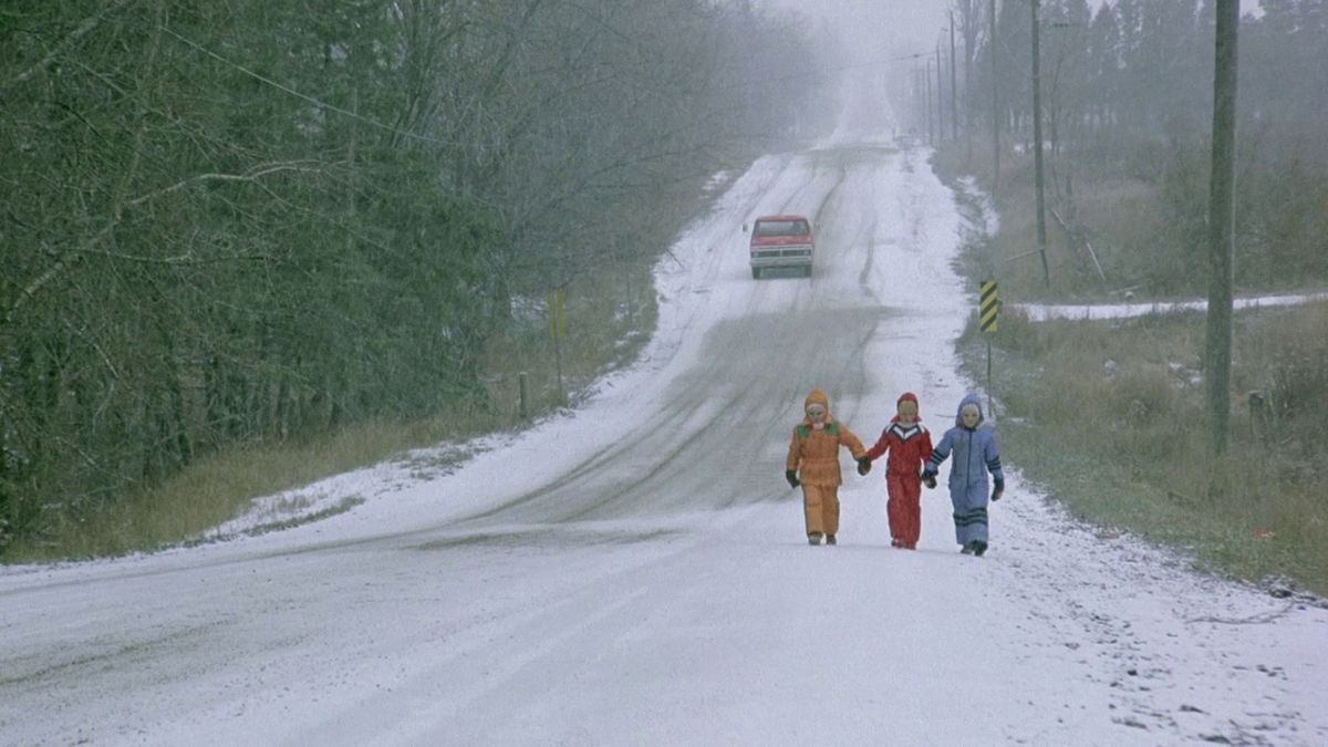 Les couvées de The Brood marchent dans une rue enneigée en combinaison de neige, se tenant la main.
