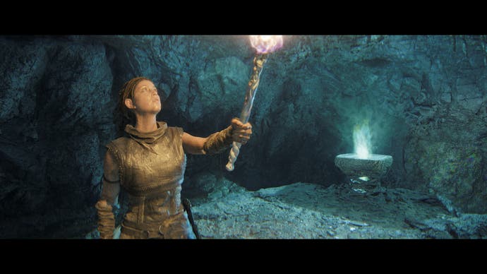 Capture d'écran de Hellblade 2 montrant Senua tenant une torche dans une petite grotte