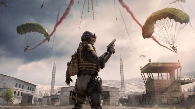 Joueur de Warzone tenant un pistolet pendant que les joueurs parachutent devant eux.
