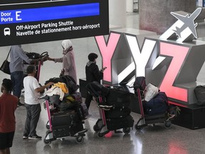 Des gens attendent avec leurs bagages à l'aéroport international Pearson de Toronto le vendredi 5 août 2022.