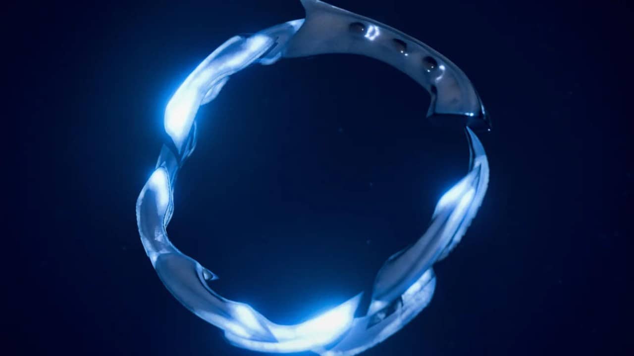 Un anneau métallique brillant avec des éléments de design torsadés sur un fond sombre, rappelant un artefact de Helldivers 2.