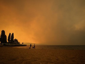 La fumée de l'incendie de forêt de McDougall Creek remplit l'air et bloque presque le soleil tandis que les gens admirent la vue sur le lac Okanagan depuis la plage Tugboat, à Kelowna, en Colombie-Britannique, le 18 août 2023.