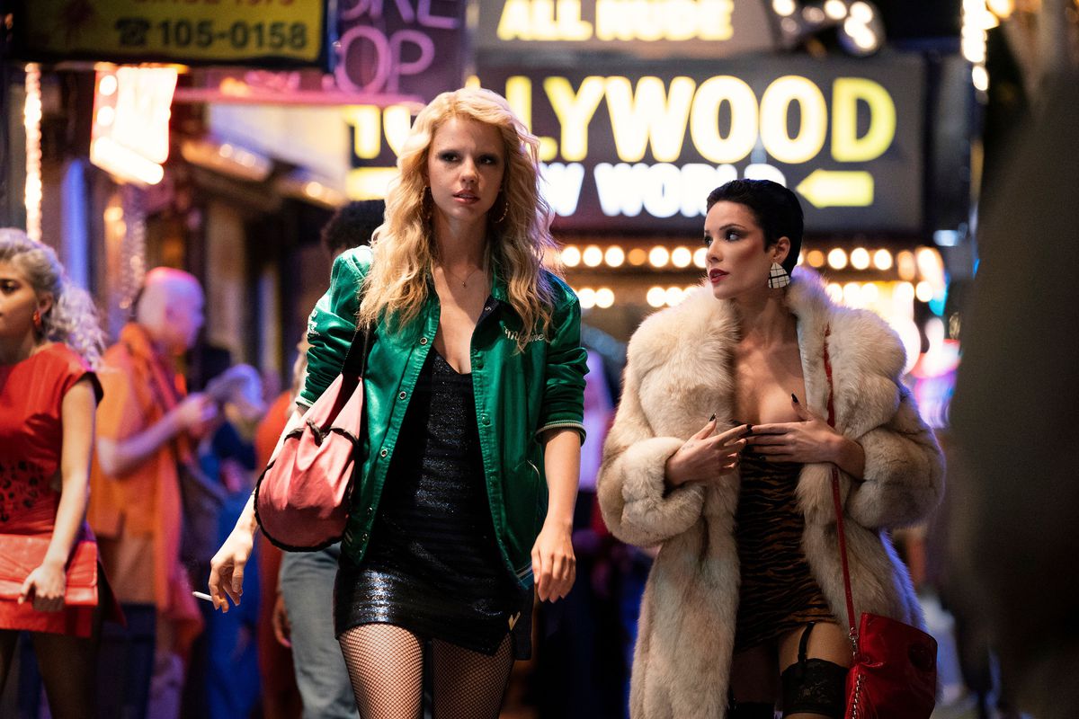 Mia Goth dans le rôle de Maxine Minx marchant dans un strip éclairé au néon de Los Angeles avec un personnage joué par Halsey dans MaXXXine