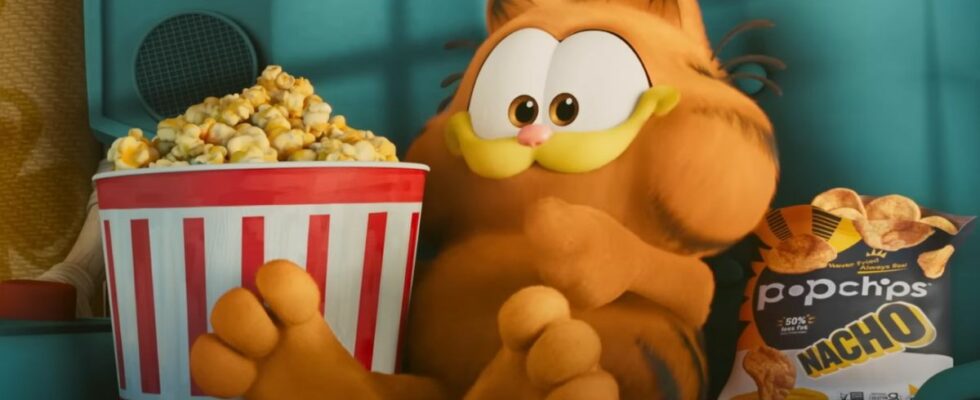 Garfield sits in a chair with a tub of popcorn in The Garfield Movie.