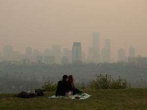 La fumée des incendies de forêt recouvre la ville alors qu'un couple pique-nique à Edmonton, le samedi 11 mai 2024.