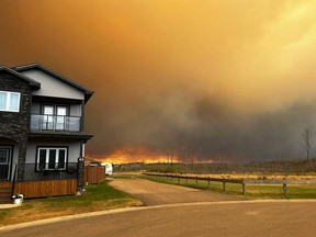 Cette image fournie gracieusement par Kosar montre la fumée et les flammes provenant de l'incendie à Fort McMurray, en Alberta, le 14 mai 2024, alors que les résidents de la région d'Abasand Heights évacuent la zone.