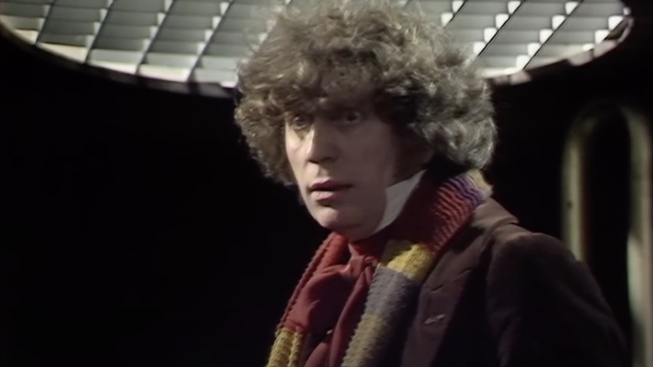 Tom Baker dans le rôle du Quatrième Docteur portant une écharpe et un manteau marron