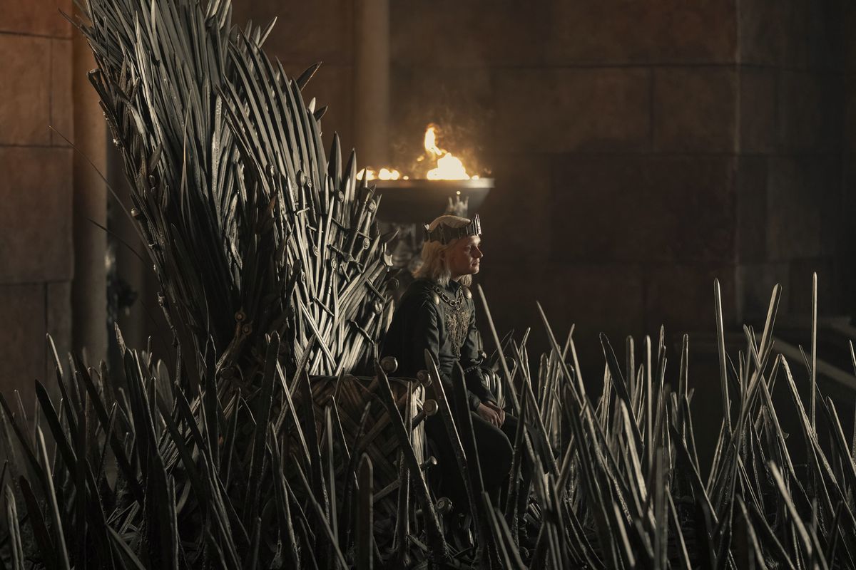 Le jeune roi Aegon est assis sur le trône de fer, presque englouti par les épées qui l'entourent lors de la première de la saison 2 de House of the Dragon.