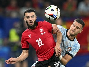 L'attaquant géorgien Georges Mikautadze se bat pour le ballon avec le défenseur portugais Diogo Dalot