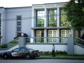 Un homme passe devant une voiture de patrouille du service de police de Vancouver devant la synagogue Schara Tzedeck, à Vancouver, en Colombie-Britannique, le vendredi 1er mai.  31, 2024.