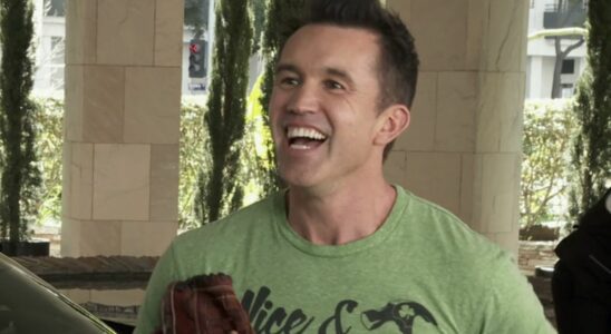 Mac smiling very wide as he holds a baseball glove while talking to Chase Utley outside a hotel in It