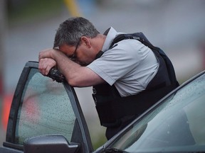 Près de 10 ans après qu'un homme perturbé armé d'un fusil a tué trois membres de la GRC à Moncton, au Nouveau-Brunswick, la GRC n'a pas encore pleinement mis en œuvre une recommandation clé d'un examen de 2014 visant à prévenir de tels affrontements meurtriers.  Un agent de la GRC repose sa tête à un barrage routier à Moncton, au Nouveau-Brunswick, le jeudi 5 juin 2014.