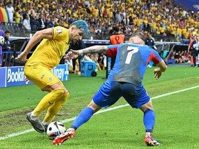 Andrei Ratiu (L), de Roumanie, se bat pour le ballon avec Tomas Suslov, de Slovaquie, à l'Euro 2024.