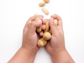Main d'enfant tenant des cacahuètes.