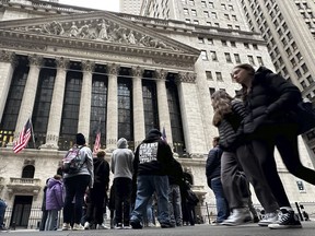 Des gens passent devant la Bourse de New York, le 27 mars 2024.