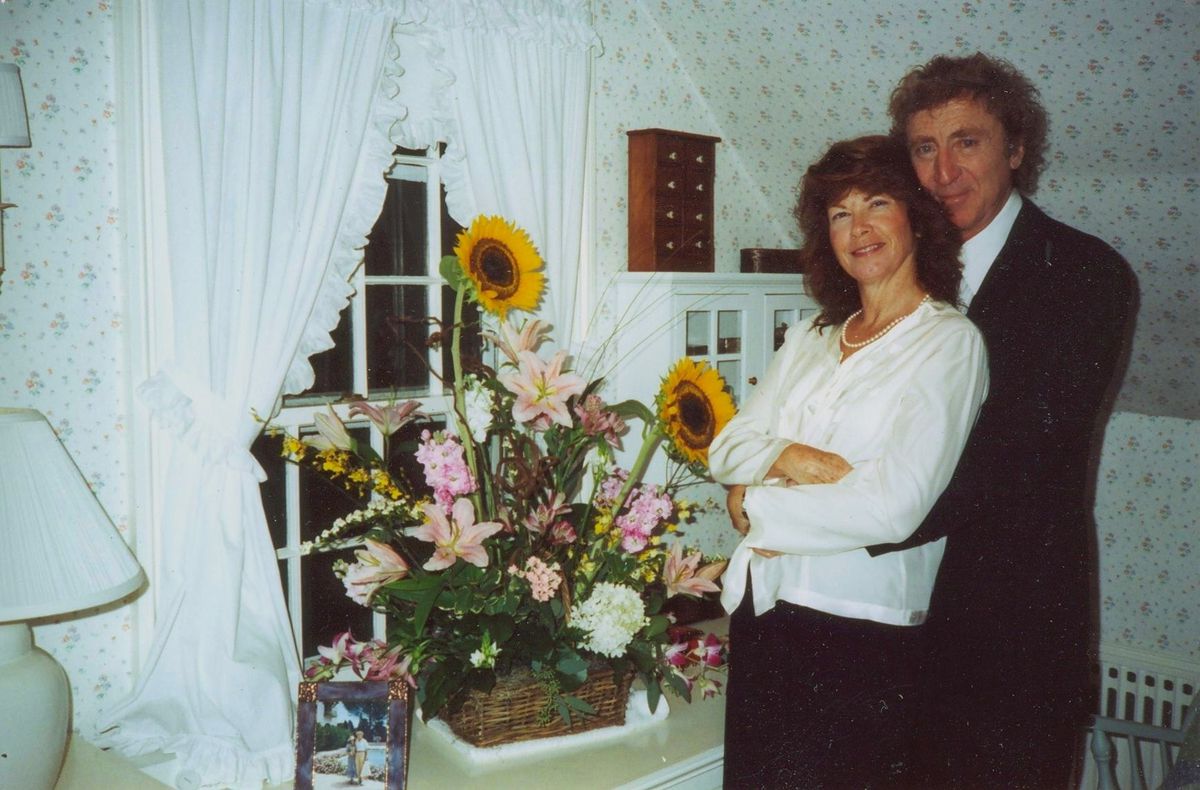 Photo d'archives de Gene Wilder debout dans une pièce avec une femme à côté d'un grand bouquet de fleurs dans Remembering Gene Wilder.