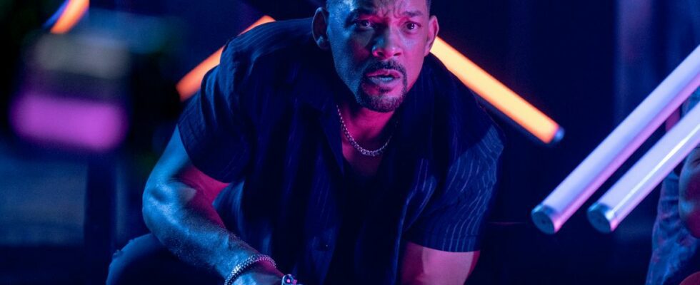 Will Smith crouched in action in a neon lit club while holding a gun in Bad Boys: Ride or Die.