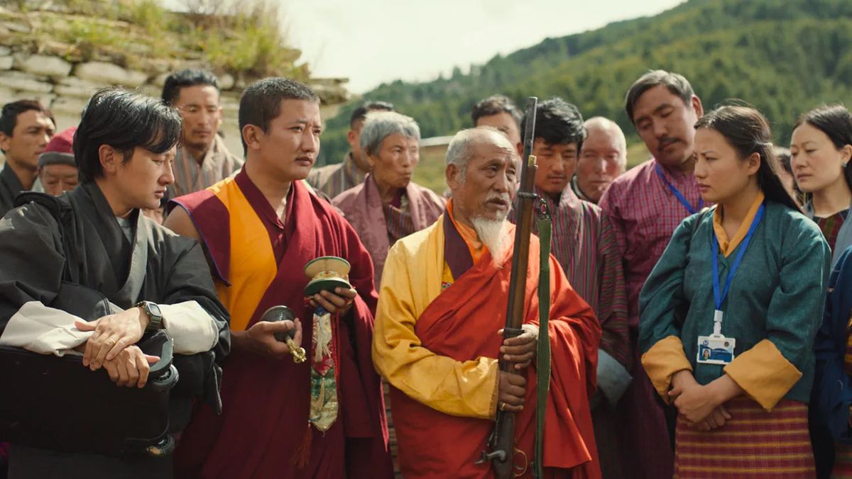 Un groupe de villageois et de moines admirant un fusil ancien.