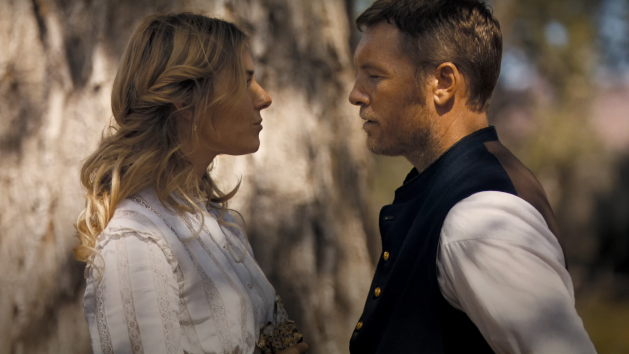 Sienna Miller et Sam Worthington se font face devant un arbre dans Horizon : An American Saga - Chapitre 1.