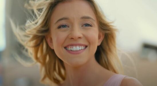 Sydney Sweeney smiling while they wind blows her hair away fromher face in Anyone But You.