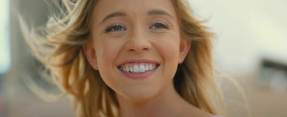 Sydney Sweeney smiling while they wind blows her hair away fromher face in Anyone But You.