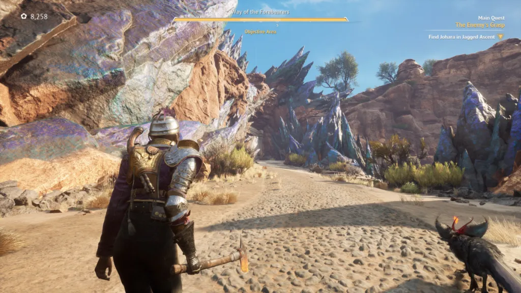 Le joueur marche sur un sentier sablonneux, avec des cristaux de couleur fluorite jaillissant des falaises de chaque côté, une créature noire ressemblant à un renard à leurs côtés