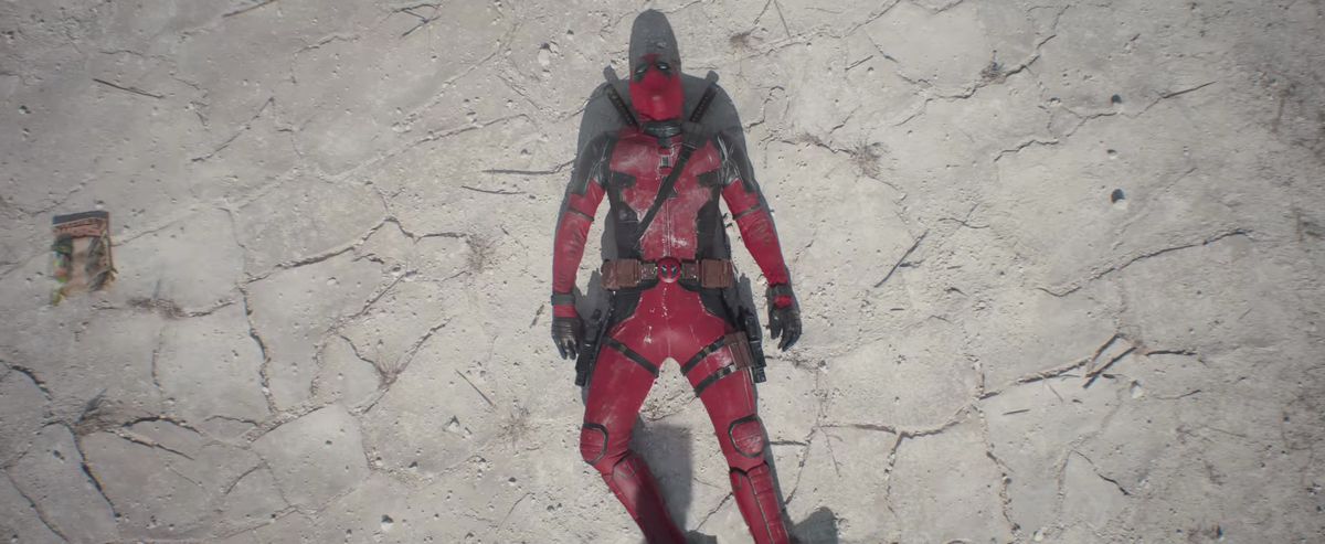 Deadpool s'évanouit sur le sol du désert à côté d'une bande dessinée Secret Wars dans Deadpool & Wolverine