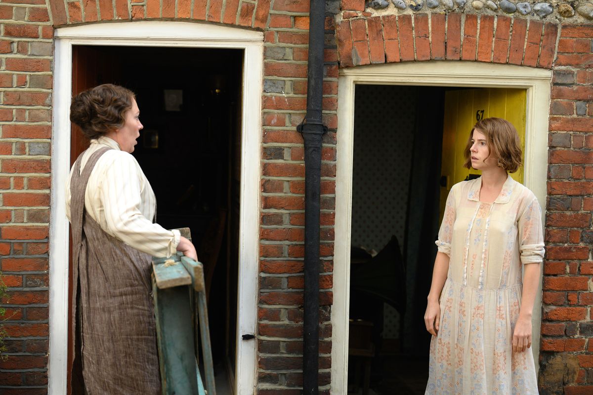 Les voisines Edith (Olivia Colman) et Rose (Jessie Buckley) se font face devant leurs portes d'entrée côte à côte dans Wicked Little Letters