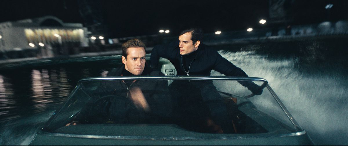 L'agent de la CIA Napoleon Solo (Henry Cavill) et l'agent du KGB Illya Kuryakin (Hammer), tous deux entièrement vêtus de noir, se tiennent ensemble dans un hors-bord la nuit lors d'une mission dans The Man From UNCLE